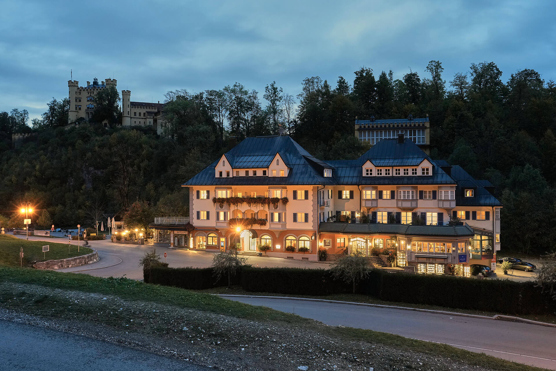 Das Hotel Müller bei Nacht mit Beleuchtung vor dunklen Bäumen